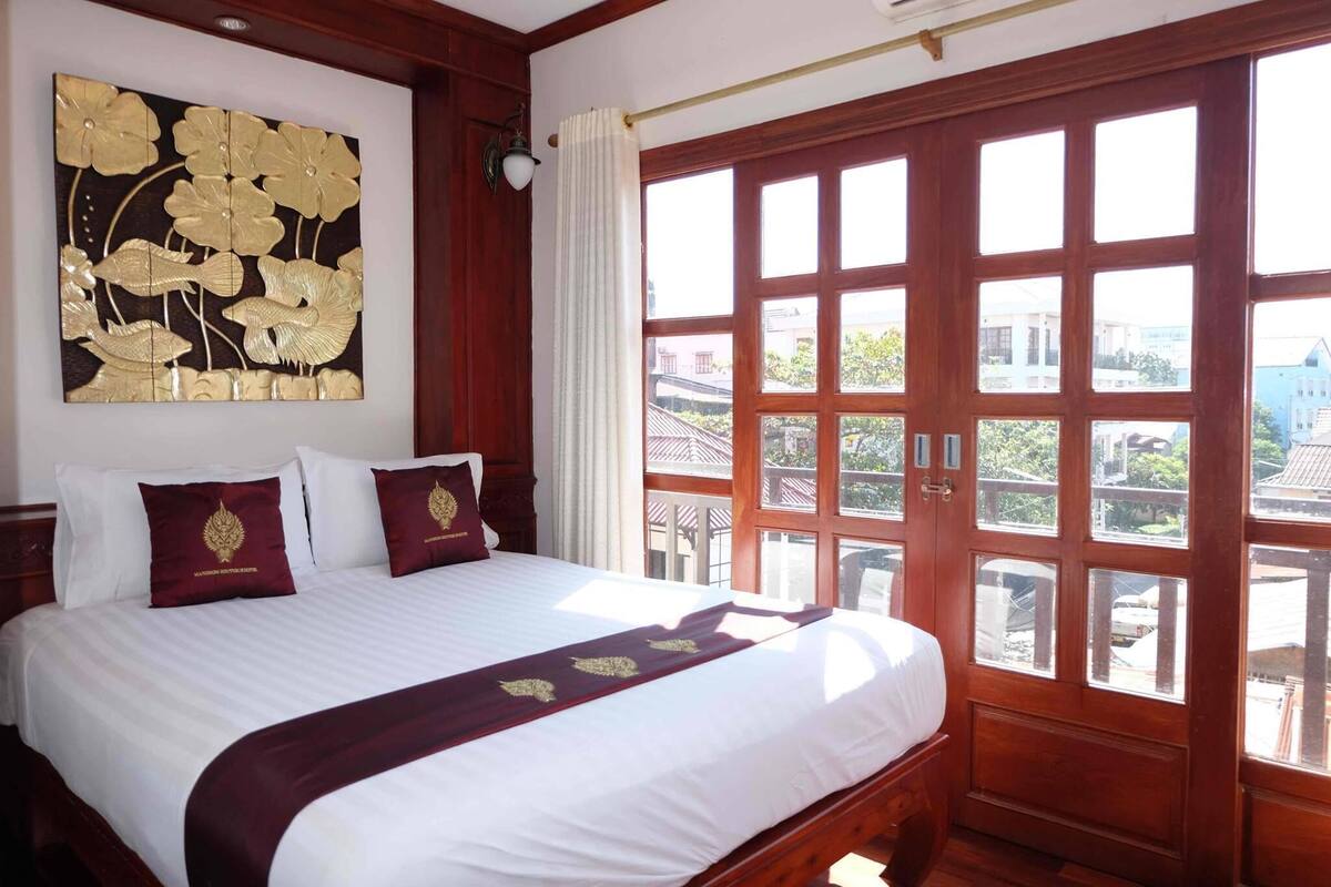 Une chambre d’hôtel avec un grand lit, un élément décoratif mural et une vue à travers une porte en bois.