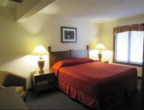 Cozy retreat with a single bed, two bedside tables, and a chair, complete with a framed picture and wall-mounted lamps.