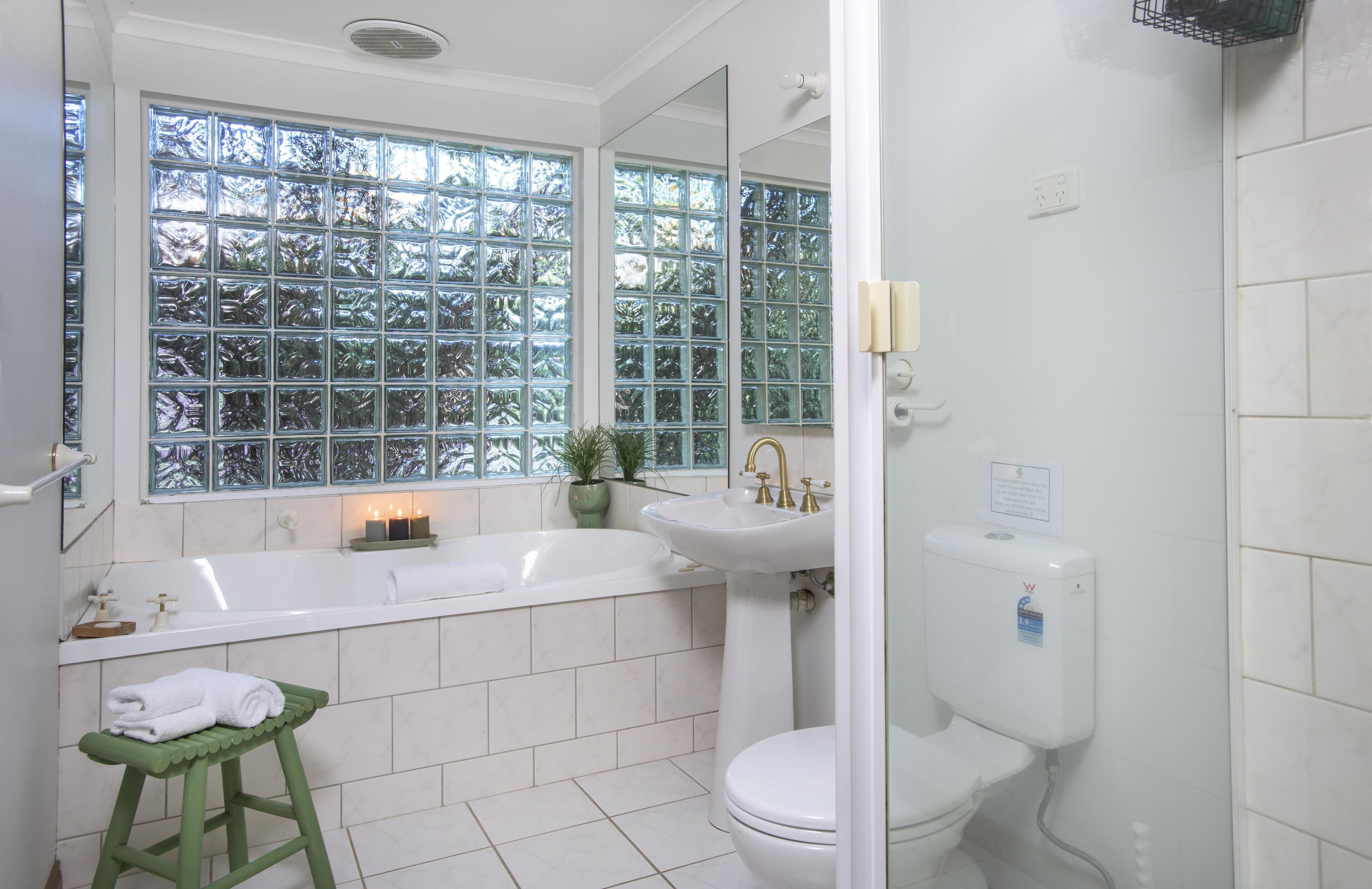A bathroom with a bathtub, sink, toilet, and a window with a view of trees.