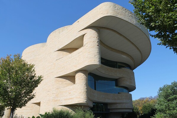 A modern building with a unique curved architecture, featuring multiple levels and large windows.