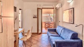 A living room with a sofa, a dining table with chairs, and a kitchen area with cabinets. - (30/45 sq m): living room with kitchenette, double sofa bed and a single folding bed, double bedroom, bathroom and balcony.<br>Features: <br>tv, <br>ironing board and iron (on request) <br>kitchenette with induction hub, <br>oven, <br>kettle, <br>microwa (Santa Teresa di Gallura)