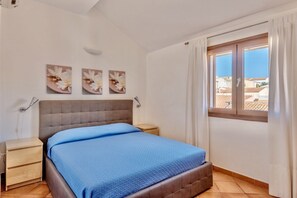 A bedroom with a bed, bedside tables, and a window with curtains. - (30/45 sq m): living room with kitchenette, double sofa bed and a single folding bed, double bedroom, bathroom and balcony.<br>Features: <br>tv, <br>ironing board and iron (on request) <br>kitchenette with induction hub, <br>oven, <br>kettle, <br>microwa (Santa Teresa di Gallura)