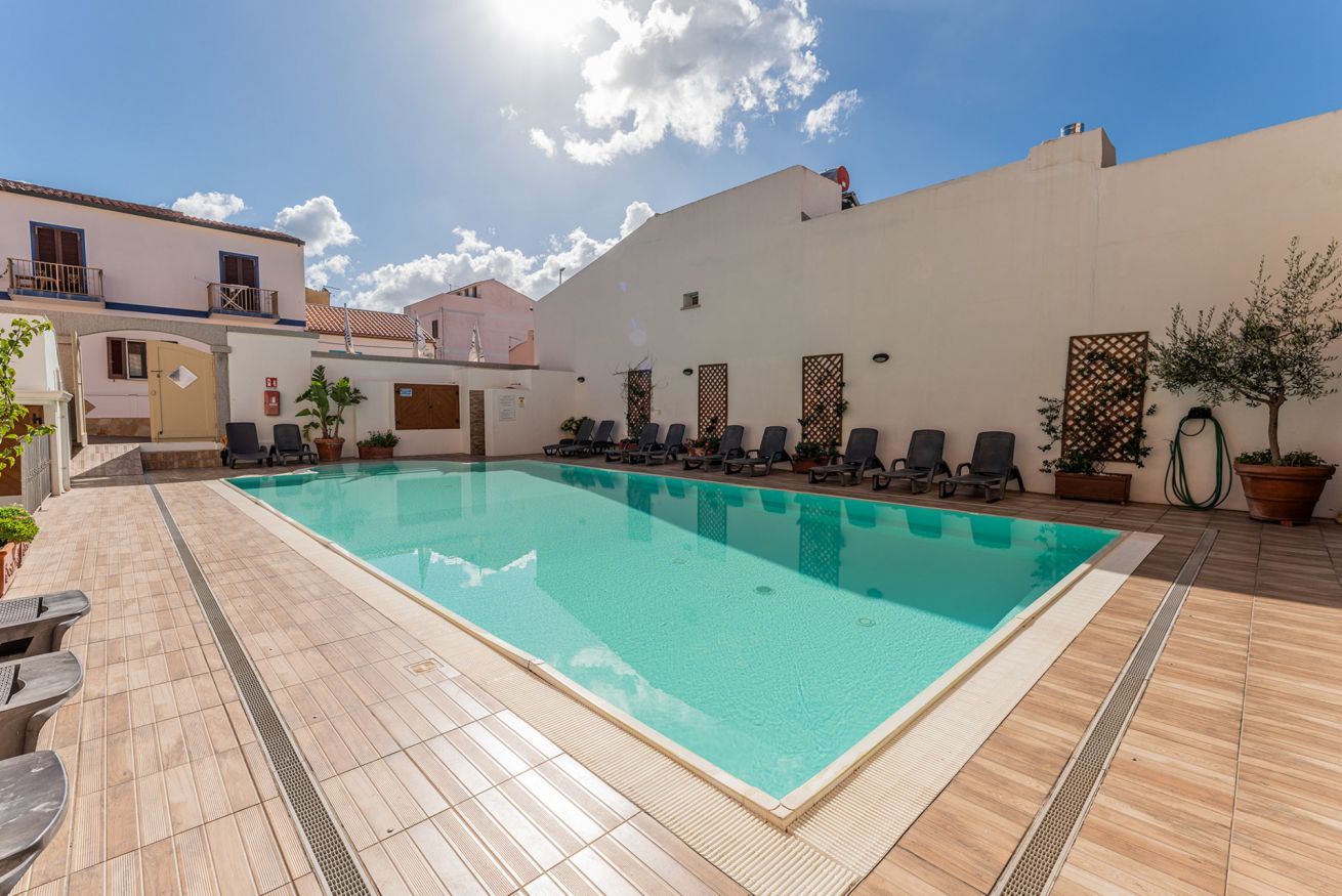 Ein Schwimmbecken mit Liegestühlen und einer gefliesten Terrasse.