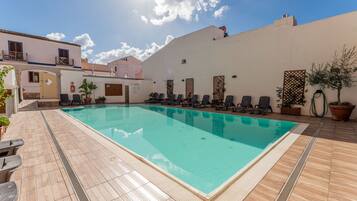 Ein Schwimmbecken mit Liegestühlen und einer gefliesten Terrasse.