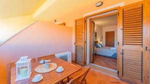 A wooden dining table with chairs, a white lantern, and a small table lamp. - (25/30 sq m): living room with kitchenette, double bed, double sofa bed or 2 single folding beds, bathroom, balcony.<br>Features: <br>tv, <br>ironing board and iron (on request) <br>kitchenette with induction hub, <br>oven, <br>kettle, <br>microwave <br> (Santa Teresa di Gallura)