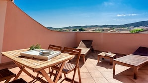 A balcony with wooden furniture, a table with a tray, and a view of a distant landscape. - (25/30 sq m): living room with kitchenette, double bed, double sofa bed or 2 single folding beds, bathroom, balcony.<br>Features: <br>tv, <br>ironing board and iron (on request) <br>kitchenette with induction hub, <br>oven, <br>kettle, <br>microwave <br> (Santa Teresa di Gallura)