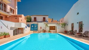 A swimming pool with a wooden deck, surrounded by buildings with balconies and potted plants. - (25/30 sq m): living room with kitchenette, double bed, double sofa bed or 2 single folding beds, bathroom, balcony.<br>Features: <br>tv, <br>ironing board and iron (on request) <br>kitchenette with induction hub, <br>oven, <br>kettle, <br>microwave <br> (Santa Teresa di Gallura)