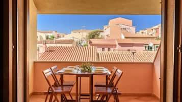 A balcony with a table set for four, overlooking a residential area with terracotta-tiled roofs.