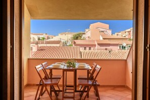 A balcony with a table set for four, overlooking a residential area with terracotta-tiled roofs.