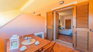A wooden dining table with chairs, a white lantern, and a small table lamp. - (20/30 sq m): living room with kitchenette, double bed, single folding bed, bathroom. <br>Features: <br>tv, <br>ironing board and iron (on request) <br>kitchenette with induction hub, <br>oven, <br>kettle, <br>microwave <br>safe, <br>1 beach umbrella, <b (Santa Teresa di Gallura)
