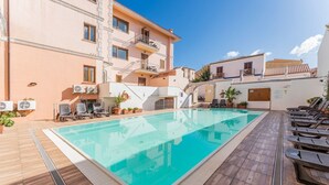 A swimming pool with lounge chairs, a covered area, and a building with balconies. - (20/30 sq m): living room with kitchenette, double bed, single folding bed, bathroom. <br>Features: <br>tv, <br>ironing board and iron (on request) <br>kitchenette with induction hub, <br>oven, <br>kettle, <br>microwave <br>safe, <br>1 beach umbrella, <b (Santa Teresa di Gallura)