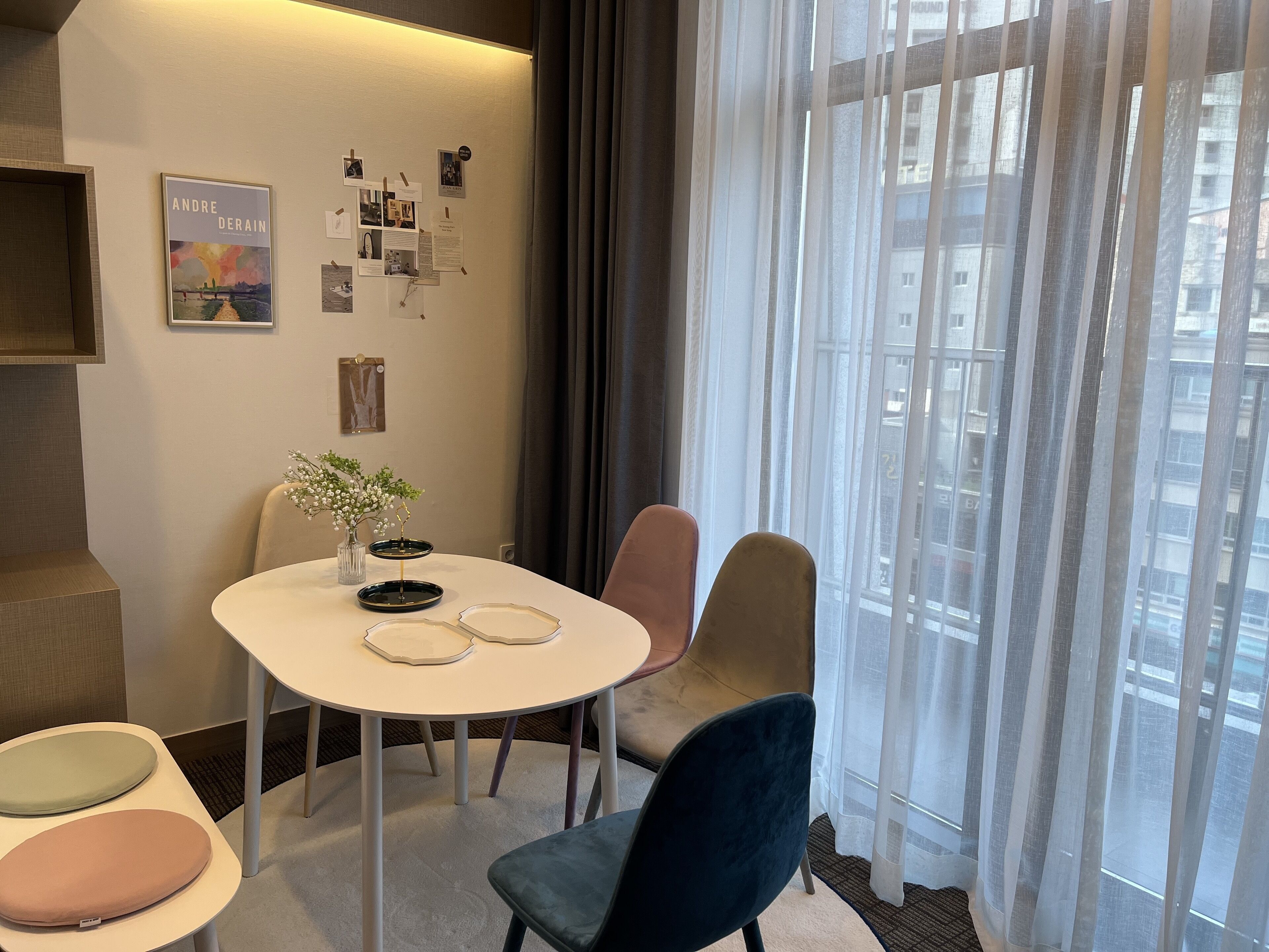 A modern hotel room with a round table, two chairs, a small plant, and a poster on the wall.
