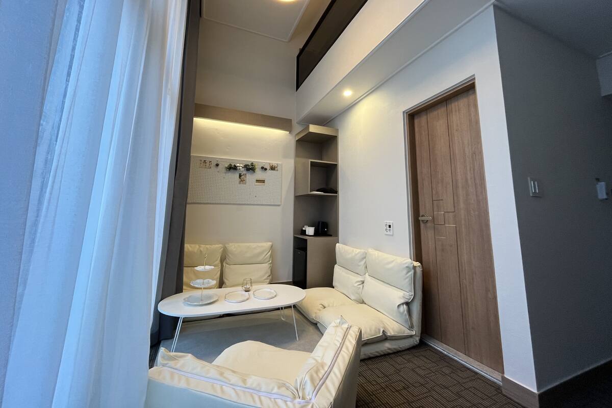 Ein modernes Hotelzimmer mit einer gemütlichen Sitzecke, einem kleinen Tisch mit Tellern und einer Holztür.