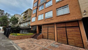 Un edificio de varios pisos de ladrillo con entrada a nivel de calle, ventanas amplias y un camino de acceso con puerta.