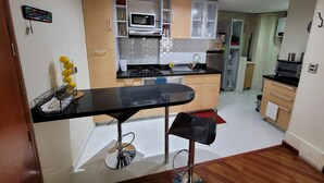 Una cocina moderna con encimera negra, electrodomésticos de acero inoxidable y armarios de madera.