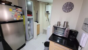 Cocina compacta con refrigerador, microondas, tostadora y un reloj en la pared.