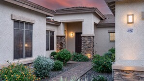 A house with a stone facade, a dark front door, and a number '20927' on the wall.