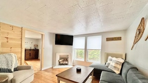 A cozy living room with a fireplace, a television, and a sign that reads "MIRROR LAKE".