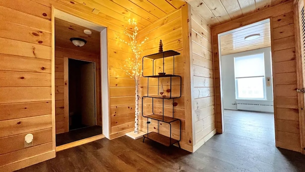 A wooden interior with a multi-tiered metal shelf, a door leading to another room, and a window allowing natural light.