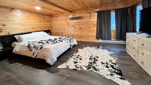 A wooden cabin bedroom with a bed, a TV, and a sign that reads "WHITEFACE".