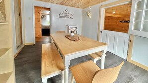 A wooden dining table with benches in a room with a high ceiling and a mounted deer head decoration.