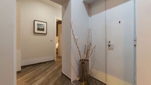 Ein Flur mit Holzboden, einer weißen Tür und einem gerahmten Bild an der Wand.