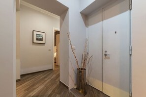 A hallway with a wooden floor, a white door, and a framed picture on the wall. - Frattina 1 - FromHometoRome (Roma)