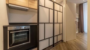 Eine moderne Küche mit einem eingebauten Backofen, einem Holzschrank darüber und einer Schiebetür zu einem Flur.