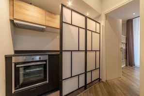 A modern kitchen with a built-in oven, a wooden cabinet above, and a sliding glass door leading to a hallway. - Frattina 1 - FromHometoRome (Roma)