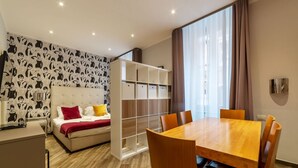 Ein modernes Hotelzimmer mit Bett, Esstisch und integriertem Kleiderschrank.