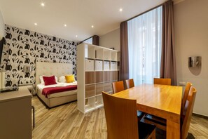 A modern hotel room with a bed, a dining table, and a built-in wardrobe.