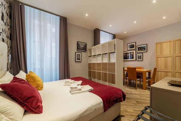 Une chambre d’hôtel comprenant un lit, un bureau, une chaise, une armoire et une table à manger.
