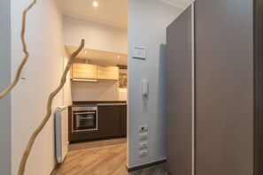 Une cuisine moderne avec des meubles en bois, un four encastré et un téléphone fixé au mur.
