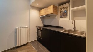 Eine kompakte Küche mit Einbauofen, Edelstahl-Spüle und einem Holzschrank über dem Herd.