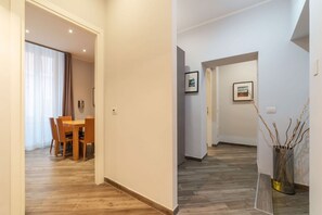 A hallway with a dining area on the left, featuring a wooden table and chairs. - Frattina 1 - FromHometoRome (Roma)