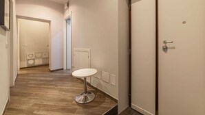 A hallway with a round table, a door, and a tiled floor. - Frattina 2 - FromHometoRome (Roma)