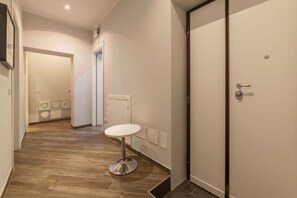 A hallway with a round table, a door, and a tiled floor. - Frattina 2 - FromHometoRome (Roma)