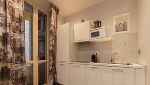 A modern kitchen with white cabinets, a microwave, a coffee maker, and a sink. - Frattina 2 - FromHometoRome (Roma)