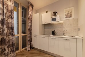 A modern kitchen with white cabinets, a microwave, a coffee maker, and a sink. - Frattina 2 - FromHometoRome (Roma)