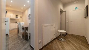 A modern hotel room with a wooden floor, a dining area with a table and chairs, a small round table, and a white wall with a door. - Frattina 2 - FromHometoRome (Roma)
