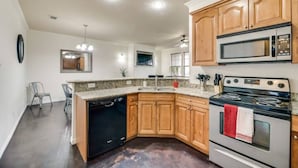 A modern kitchen with wooden cabinets, a built-in oven, a microwave, and a dishwasher. - Spacious Farmhouse  Townhome*Walk to AT&T Stadium* (Arlington)