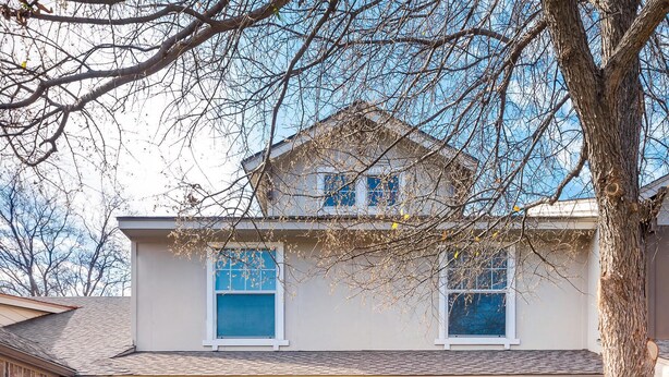A two-story house with a front porch, a brick exterior, and a small garden area. - Spacious Farmhouse  Townhome*Walk to AT&T Stadium* (Arlington)