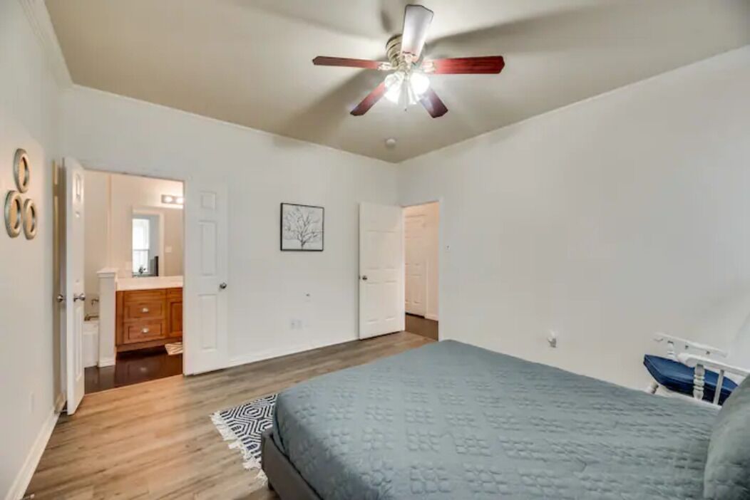 A bedroom with a bed, a ceiling fan, and a door leading to a bathroom.