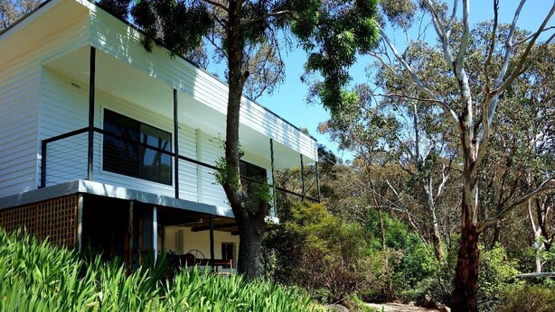 Uma casa moderna com telhado plano, janelas amplas e varanda coberta.