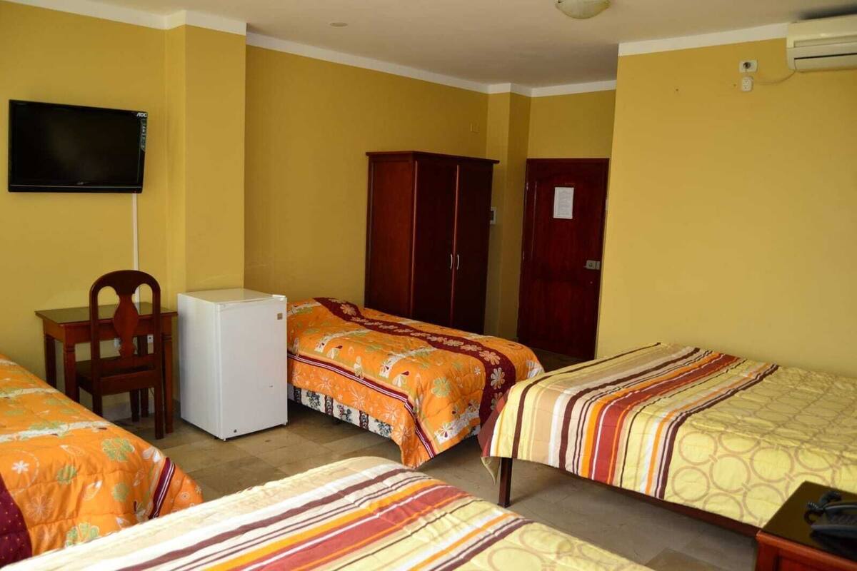 A room with two beds, a desk, a chair, a television, and a wardrobe.