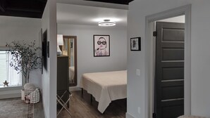 A bedroom with a bed, a bedside table, a lamp, and a window with a star decoration. - The 418 ~ An 1866 Build with Modern Comforts (Fort Wayne)