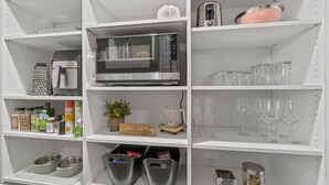 A kitchen with a microwave, toaster, and various kitchen utensils on shelves. - The 418 ~ An 1866 Build with Modern Comforts (Fort Wayne)