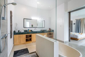 Enjoy a refreshing shower in the sleek shower enclosure with a handheld showerhead and large mirror above the vanity.