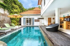 Relax by the pool surrounded by a lush green wall and comfortable lounge seating.