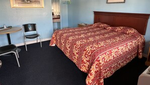 Une chambre d’hôtel avec un lit, un bureau, une chaise et deux tableaux encadrés accrochés aux murs.
